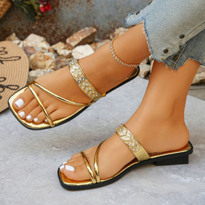 Gold flat sandals with rhinestone embellished straps and thin toe straps.