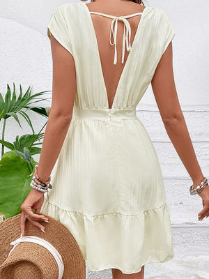 Tiered cap sleeve mini dress in pale yellow with a deep V-back and tie detail.