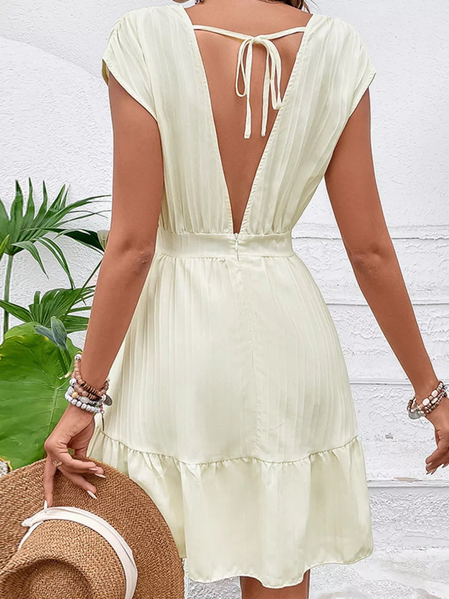 Tiered cap sleeve mini dress in pale yellow with a deep V-back and tie detail.