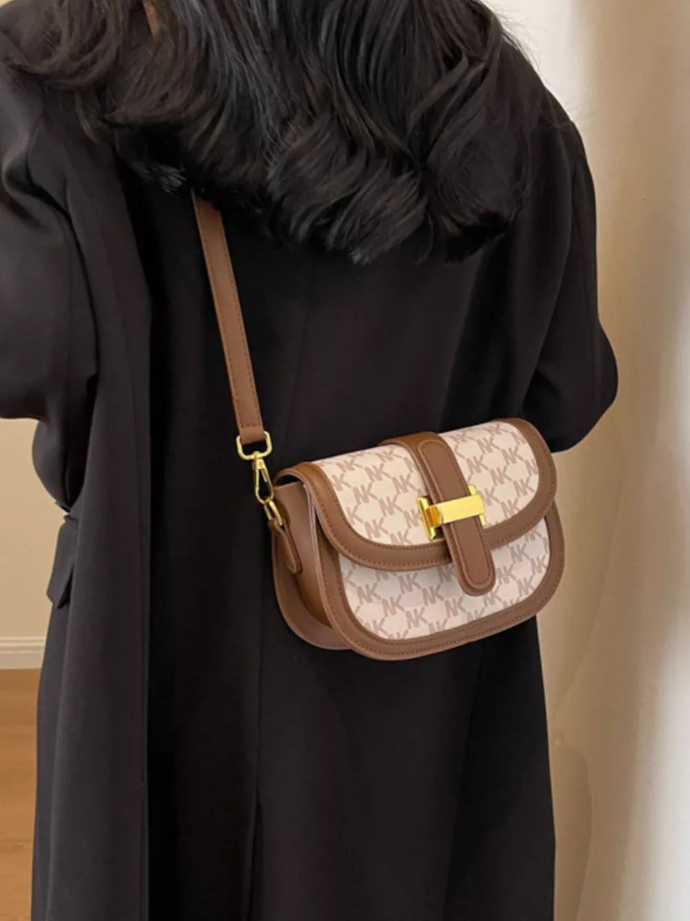 Chic monogram crossbody bag in tan and cream with brown trim and gold buckle.