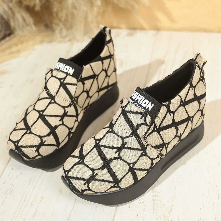 Beige and black geometric patterned slip-on sneakers with platform soles.