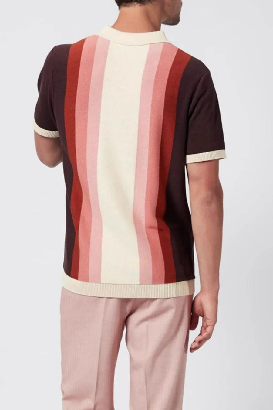 Gradient stripe knit polo shirt with cream, pink, and red stripes on a dark brown background.