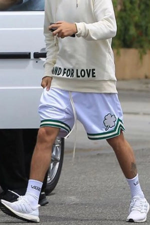 White mesh basketball shorts with green trim and clover logo