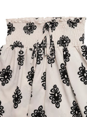 White shorts with black medallion print, smocked waist, and drawstring detail.