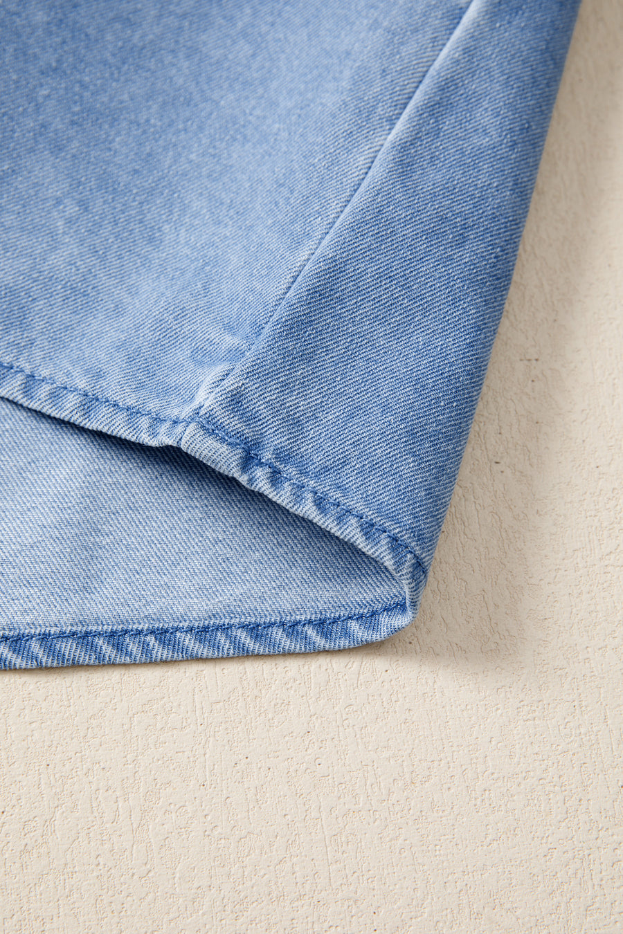 Light blue distressed denim top with visible stitching detail