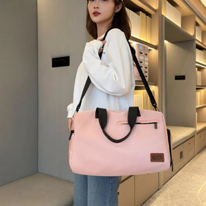Pink nylon travel duffel bag with black straps and zipper pockets, worn by a woman.