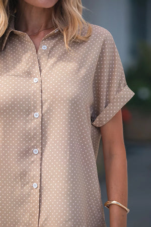 Chic polka dot button-up blouse with cuffed short sleeves and a collared neckline.