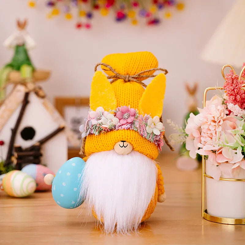Easter gnome with yellow bunny ears hat, floral crown, white beard, holding blue egg.