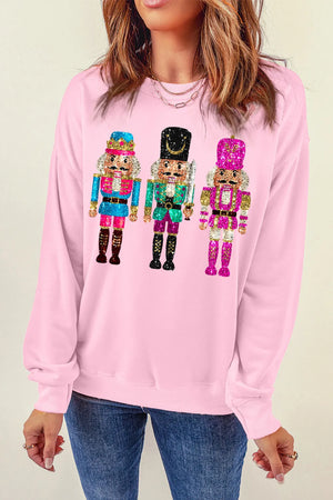 Blush pink crewneck sweatshirt with a graphic of three sequined nutcrackers.