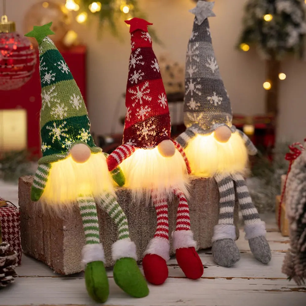 Illuminated knit gnomes in red, dark gray, and dark green with snowflake patterns and fuzzy beards.