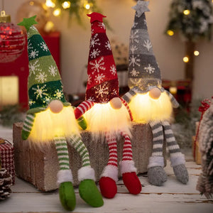 Illuminated knit gnomes in red, dark gray, and dark green with snowflake patterns and fuzzy beards.