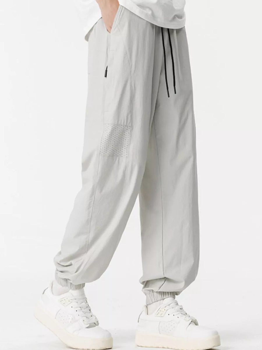 Lightweight jogger sweatpants in light gray with drawstring and perforated detail.
