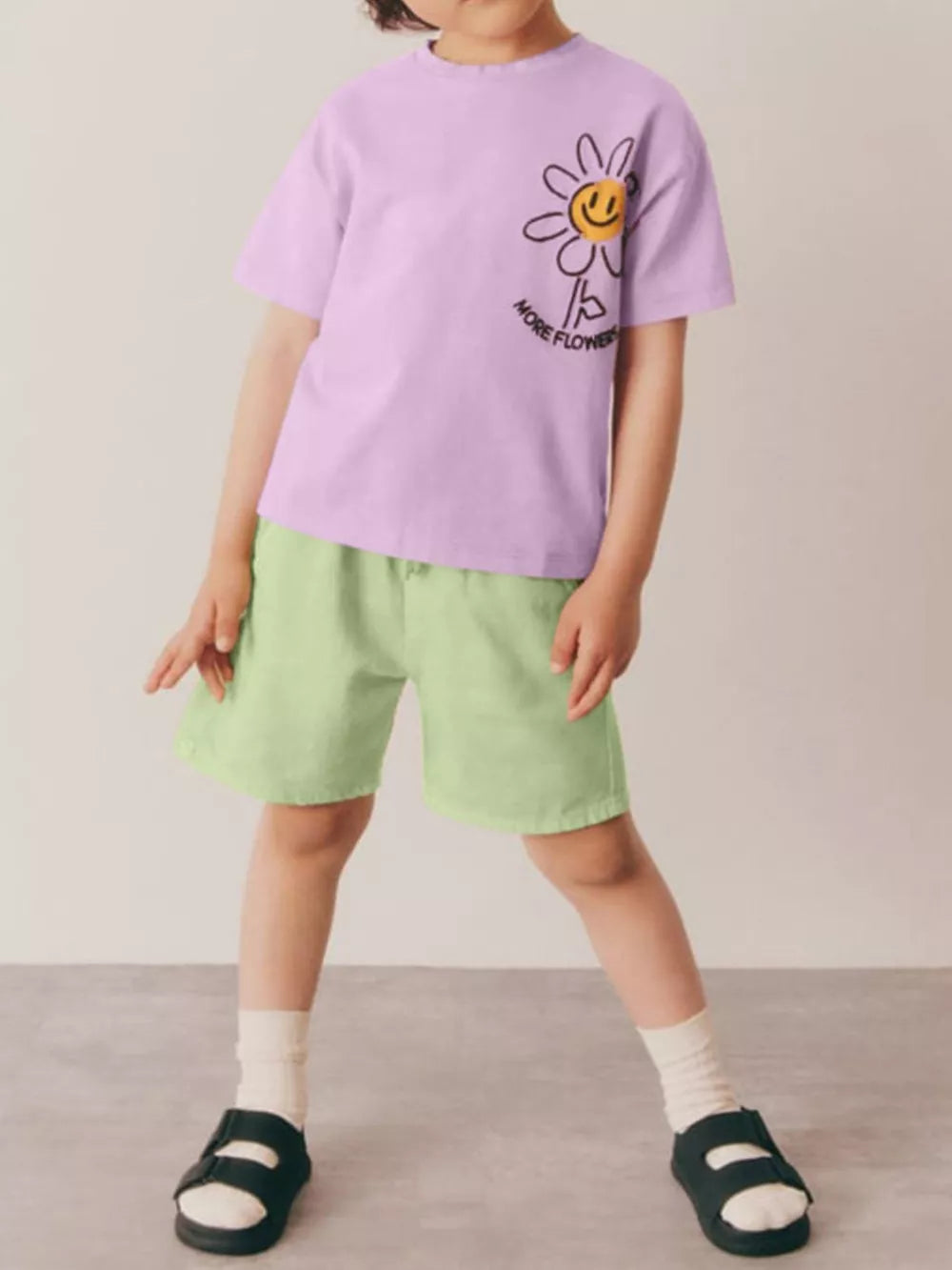 Girls' lavender cotton blend tee with daisy graphic and light green shorts.