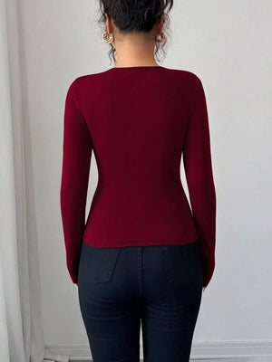 Burgundy long-sleeve tee with asymmetrical cutout detail, fitted silhouette.