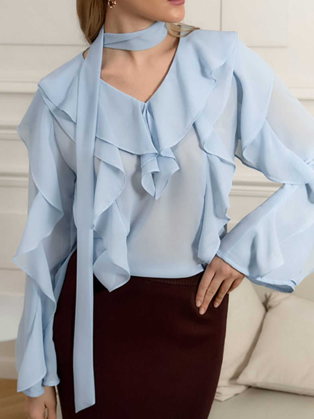 Light blue chiffon blouse with V-neck, ruffle trim, and tie detail.