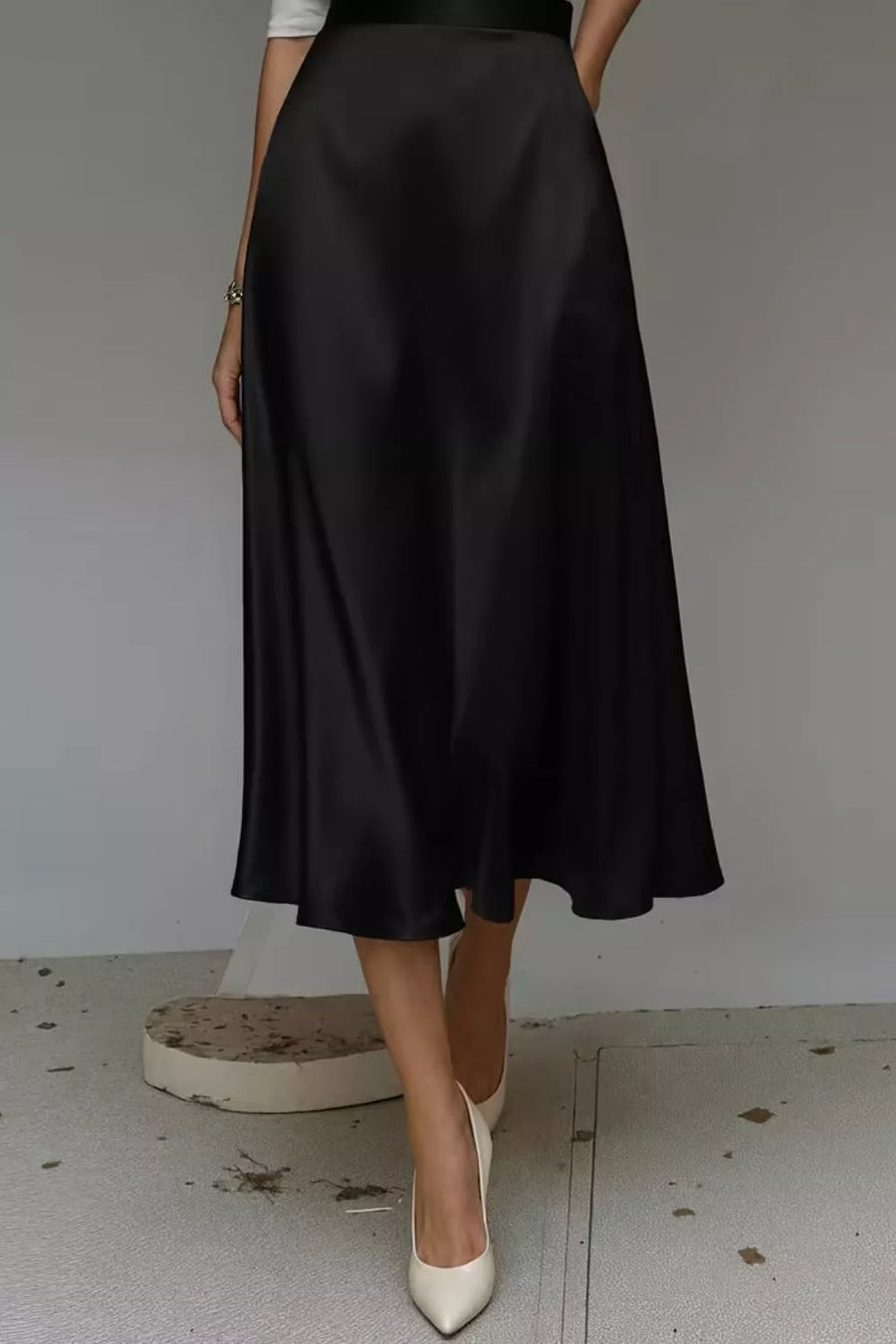 Black a-line midi skirt with hidden pockets, made of lustrous fabric.