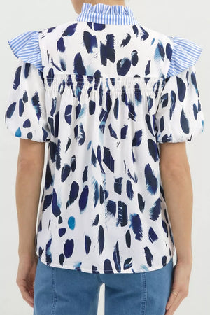 White polyester shirt with abstract blue brushstroke print, ruffled blue striped collar and sleeves.