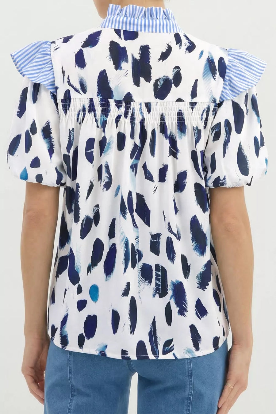 White polyester shirt with abstract blue brushstroke print, ruffled blue striped collar and sleeves.