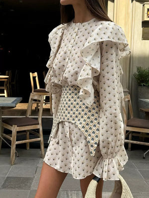Cream printed mini dress with ruffled sleeves and a patterned vest.
