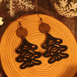 Black laser-cut pine tree earrings with wooden circle tops and copper hooks.