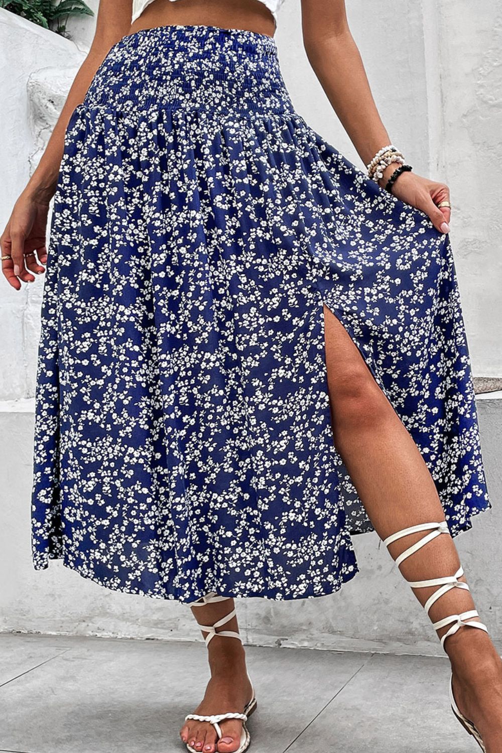 Ditsy floral midi skirt with a high slit and smocked waist, styled with white gladiator sandals.