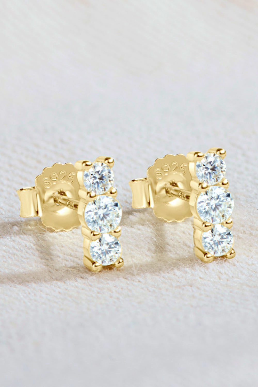 Gold triple stone bar stud earrings with clear cubic zirconia accents.