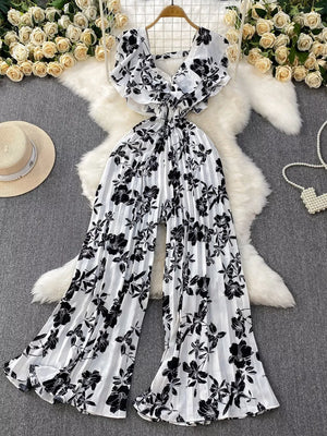 Black and white floral pleated wide-leg romper with ruffled sleeves and V-neck.