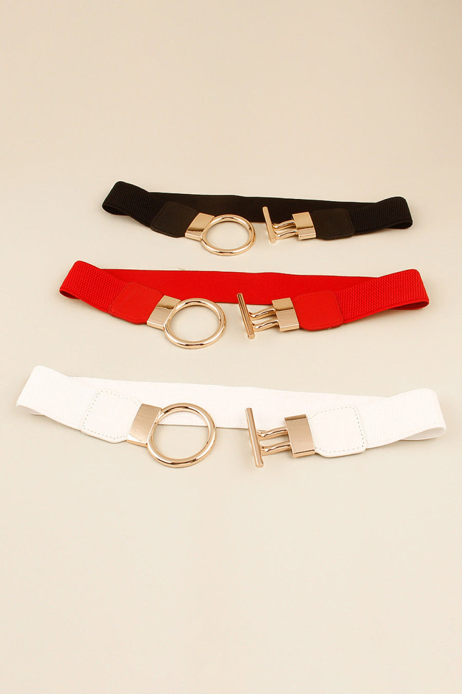 Elasticated ring buckle belts in black, red, and white with gold-tone alloy hardware.