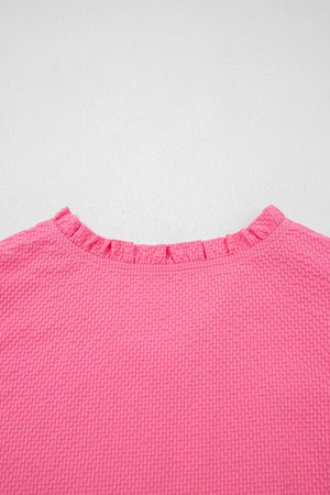 Women's pink textured blouse with a ruffled neckline