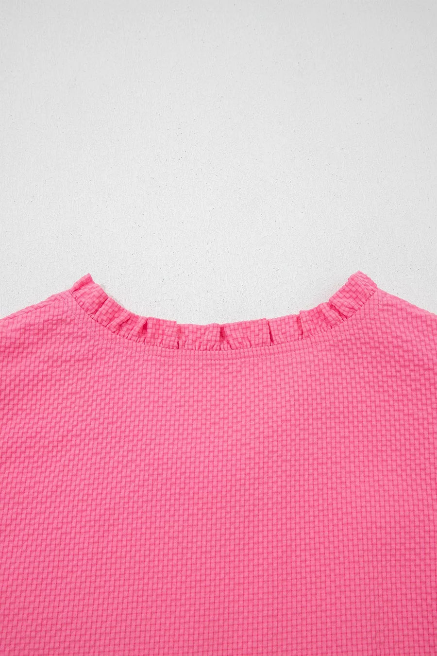 Women's pink textured blouse with a ruffled neckline