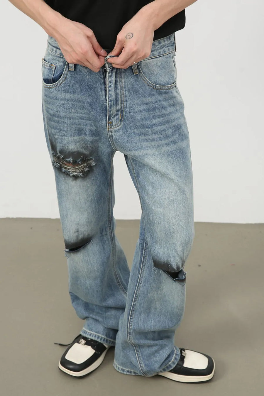 Distressed flare leg jeans in medium wash denim with ripped knee details.