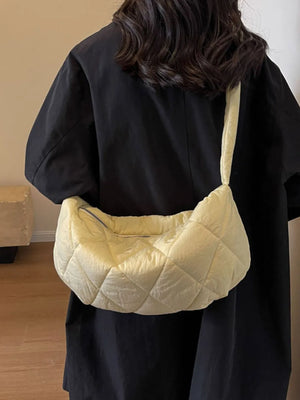 Quilted crossbody bag in pastel yellow with a zippered closure and adjustable strap.