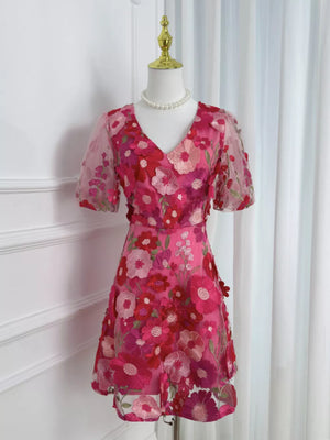 Pink floral embroidered dress with V-neck, short puff sleeves, and sheer overlay.