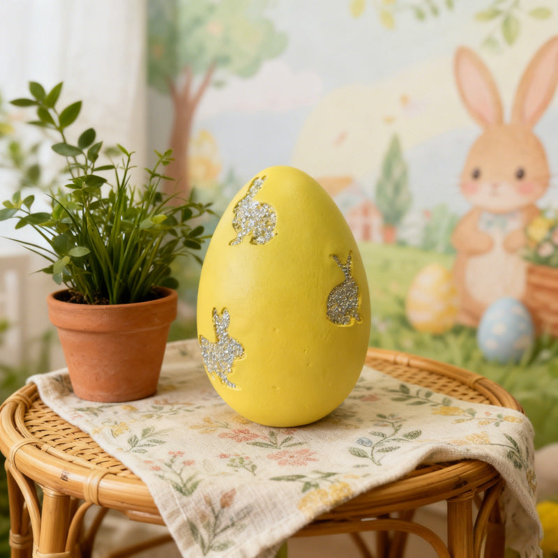 Yellow Easter egg decor with glitter bunny cutouts on a floral cloth.