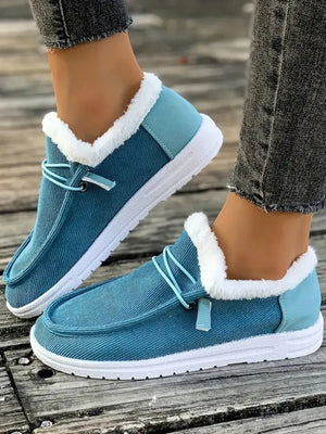 Pastel blue corduroy slip-on sneakers with white faux fur lining and light blue heel detail.