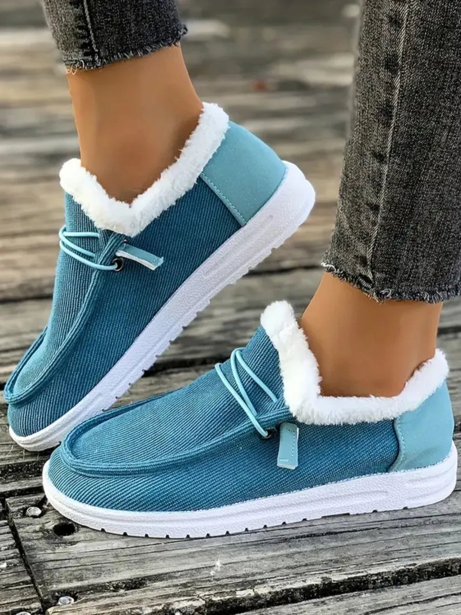 Pastel blue corduroy slip-on sneakers with white faux fur lining and light blue heel detail.