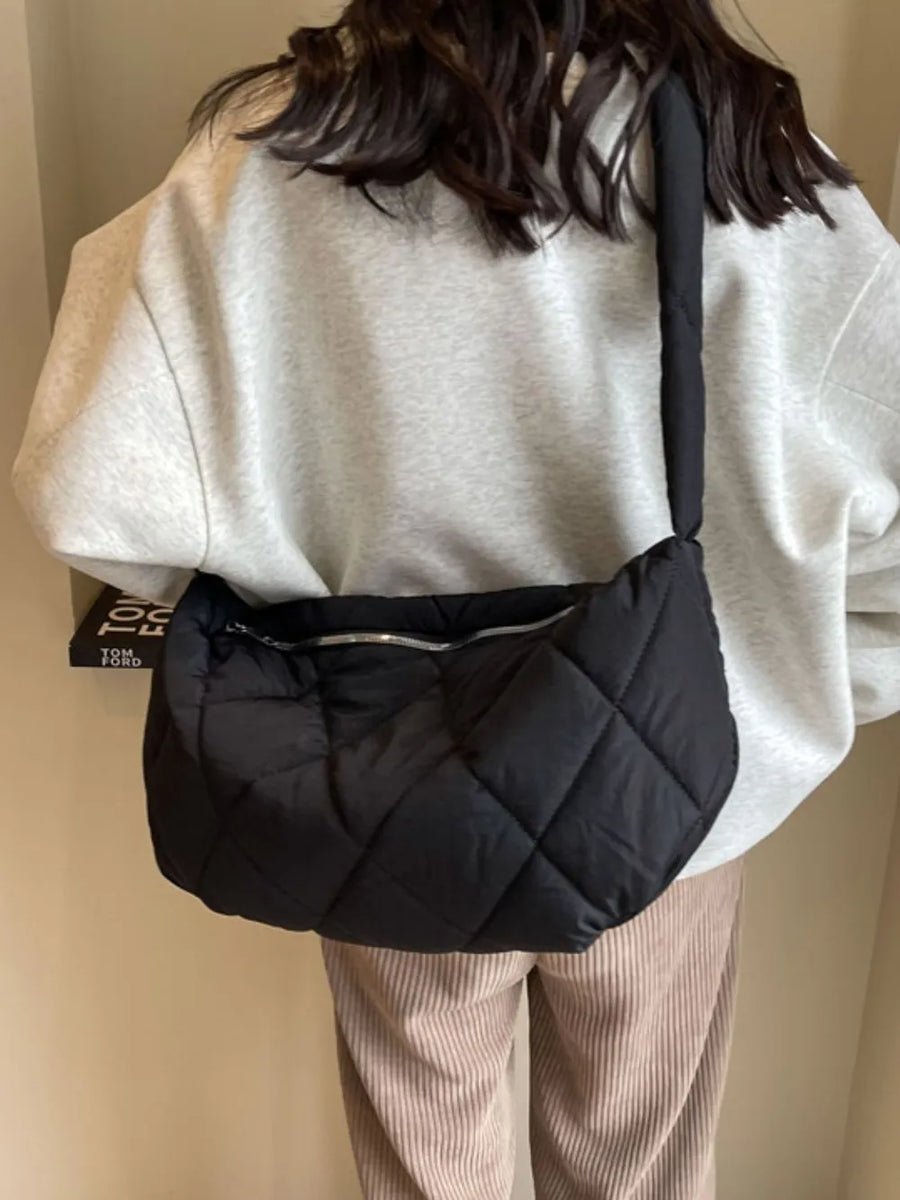 Black quilted crossbody bag with a silver zipper detail and a padded strap.
