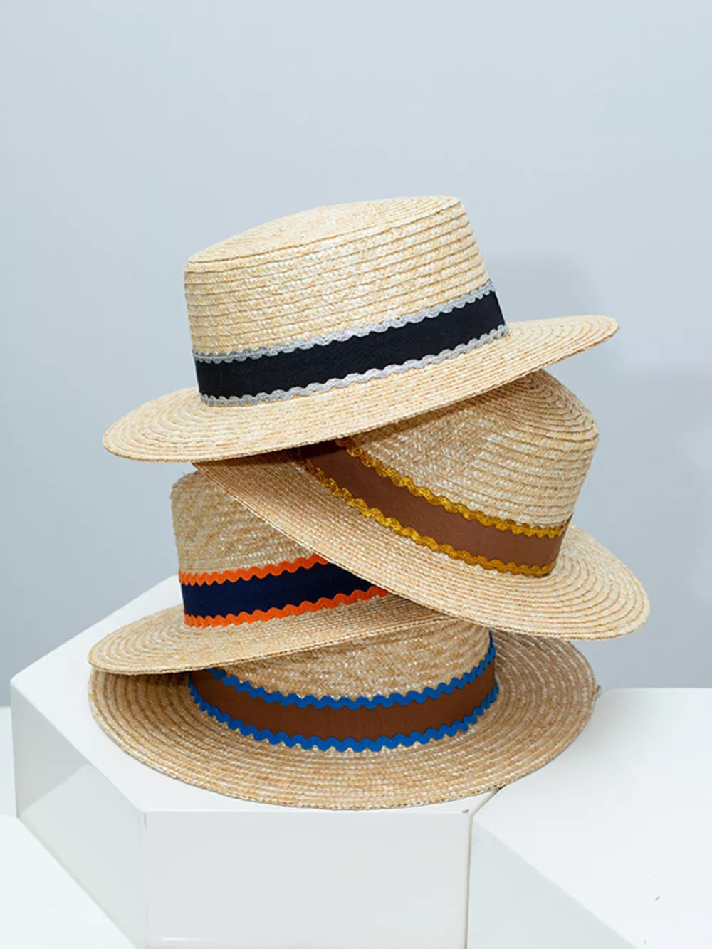 Straw boater hats with decorative bands in blue, orange-red, and brown.