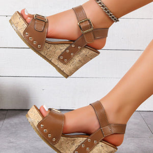 Brown studded high wedge sandals with ankle straps and buckle closure.