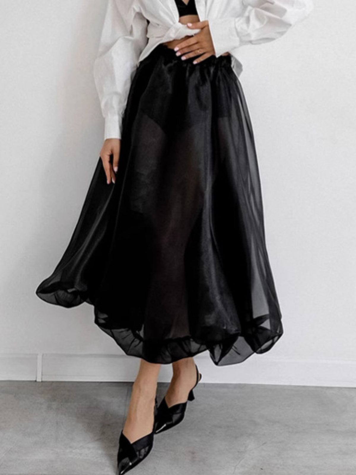Black midi skirt with sheer overlay and elastic waistband, styled with heels.