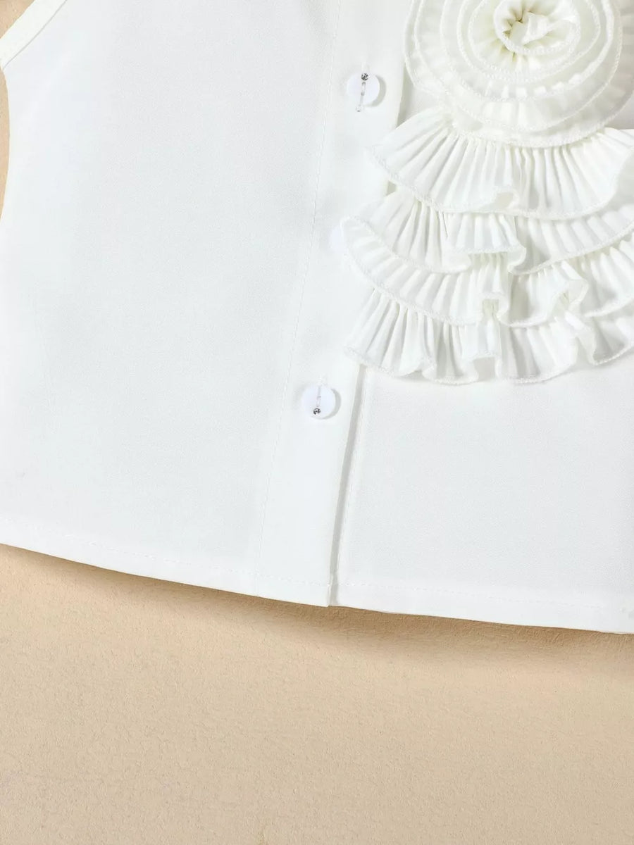 White ruffled top with decorative button detail and layered ruffles.