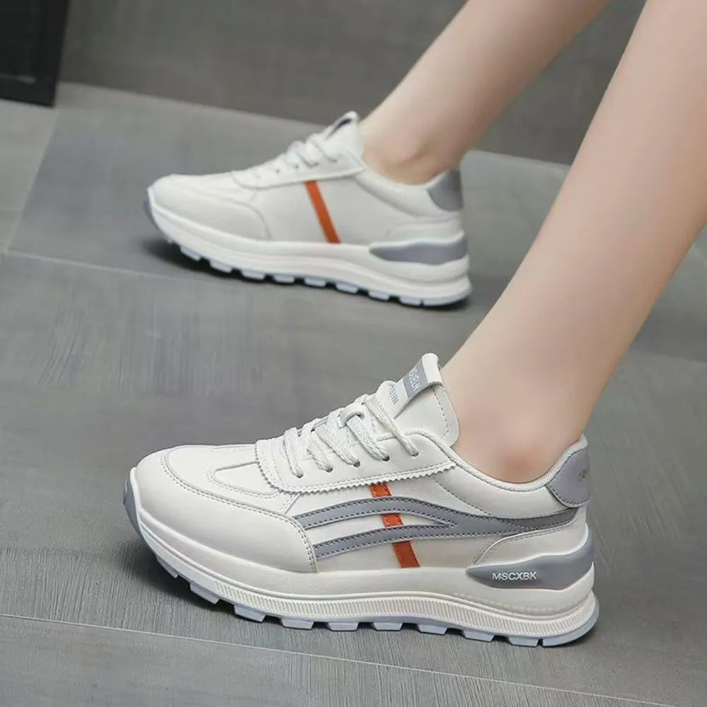 White platform sneakers with gray and orange contrast stripes and chunky sole.