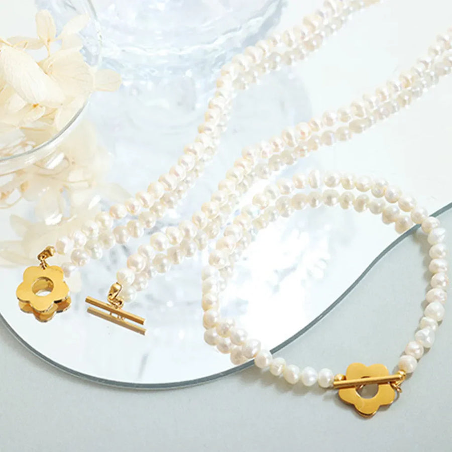 Pearl Petal Pearl Bracelet in gold features a double strand of pearls with a flower clasp.