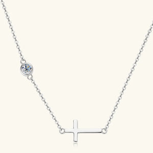 Silver asymmetrical cross pendant necklace with a single clear stone accent.