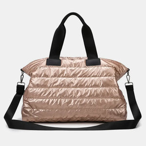 Glossy padded weekend holdall in rose gold with black straps and silver hardware.