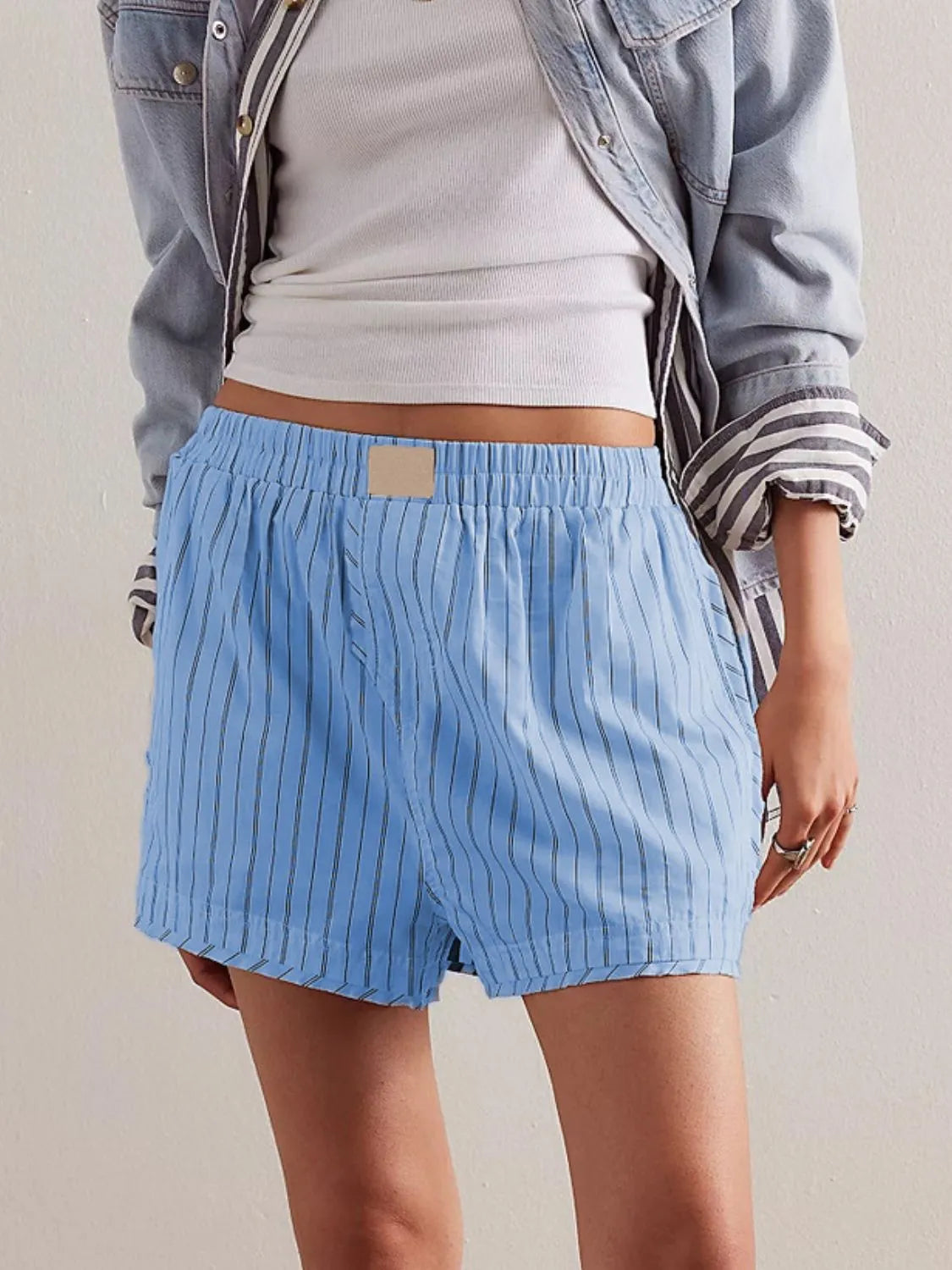 Light blue boxer shorts with black pinstripes, elastic waistband, and a square patch detail.