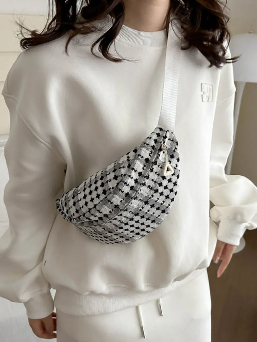 Textured houndstooth belt bag in black and white with a white adjustable strap.