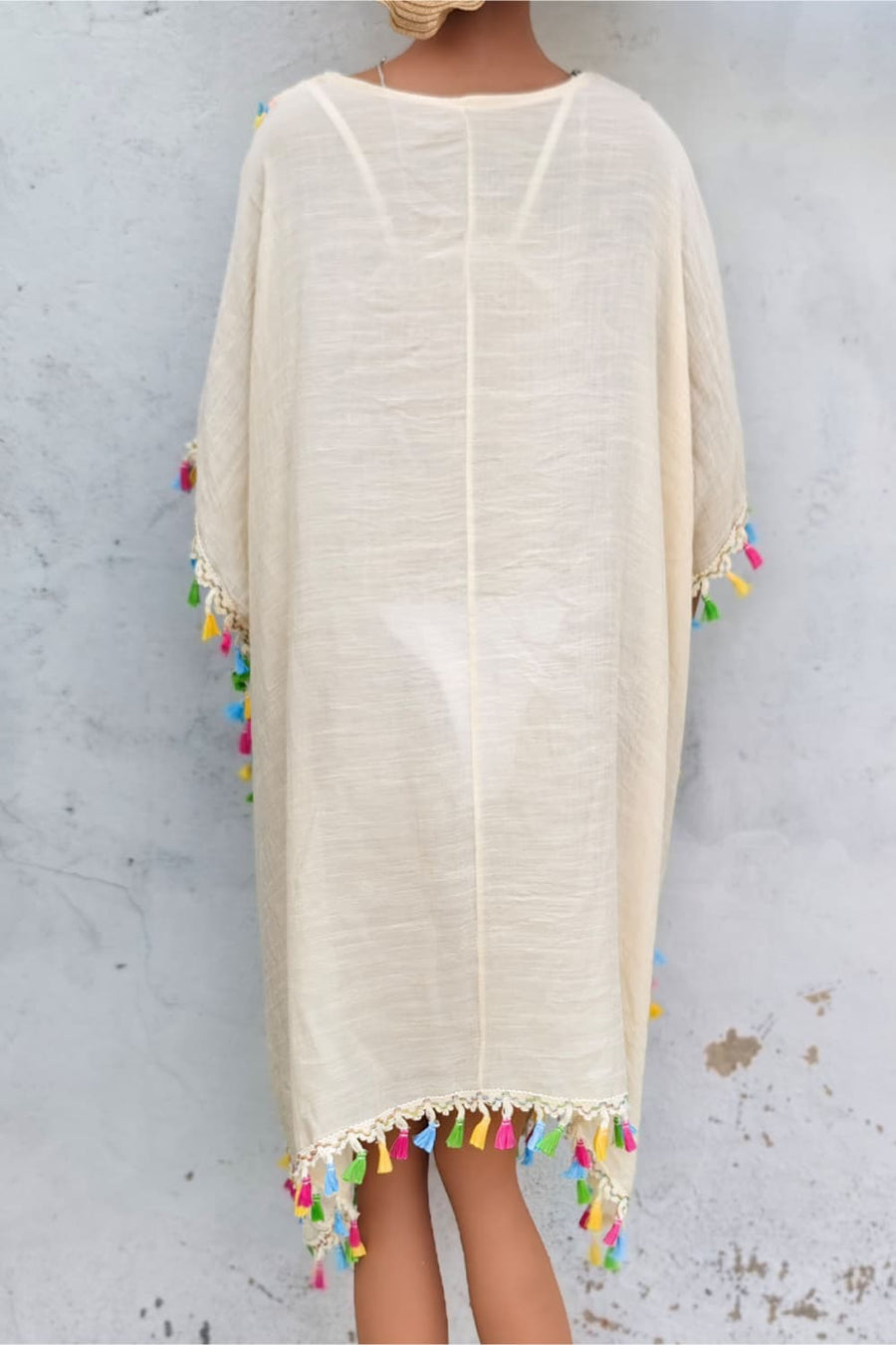 Beige kaftan dress with crochet yoke and colorful tassel trim.