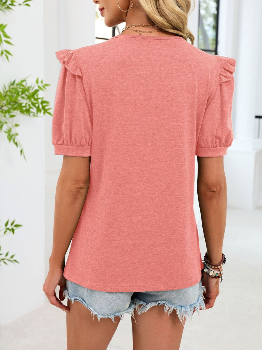 Pink ruffled V-neck short-sleeve t-shirt with elastic cuffs, styled with denim shorts.