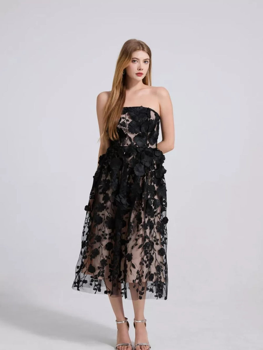 Black strapless midi dress with intricate floral applique and sheer overlay.